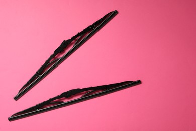 Car windshield wipers on pink background, flat lay