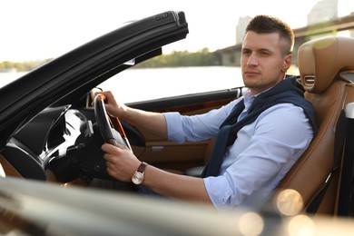 Photo of Stylish man driving luxury convertible car outdoors