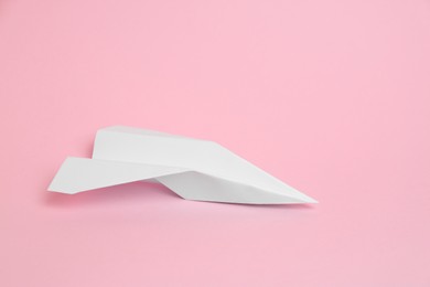 Photo of White paper plane on pink background, space for text