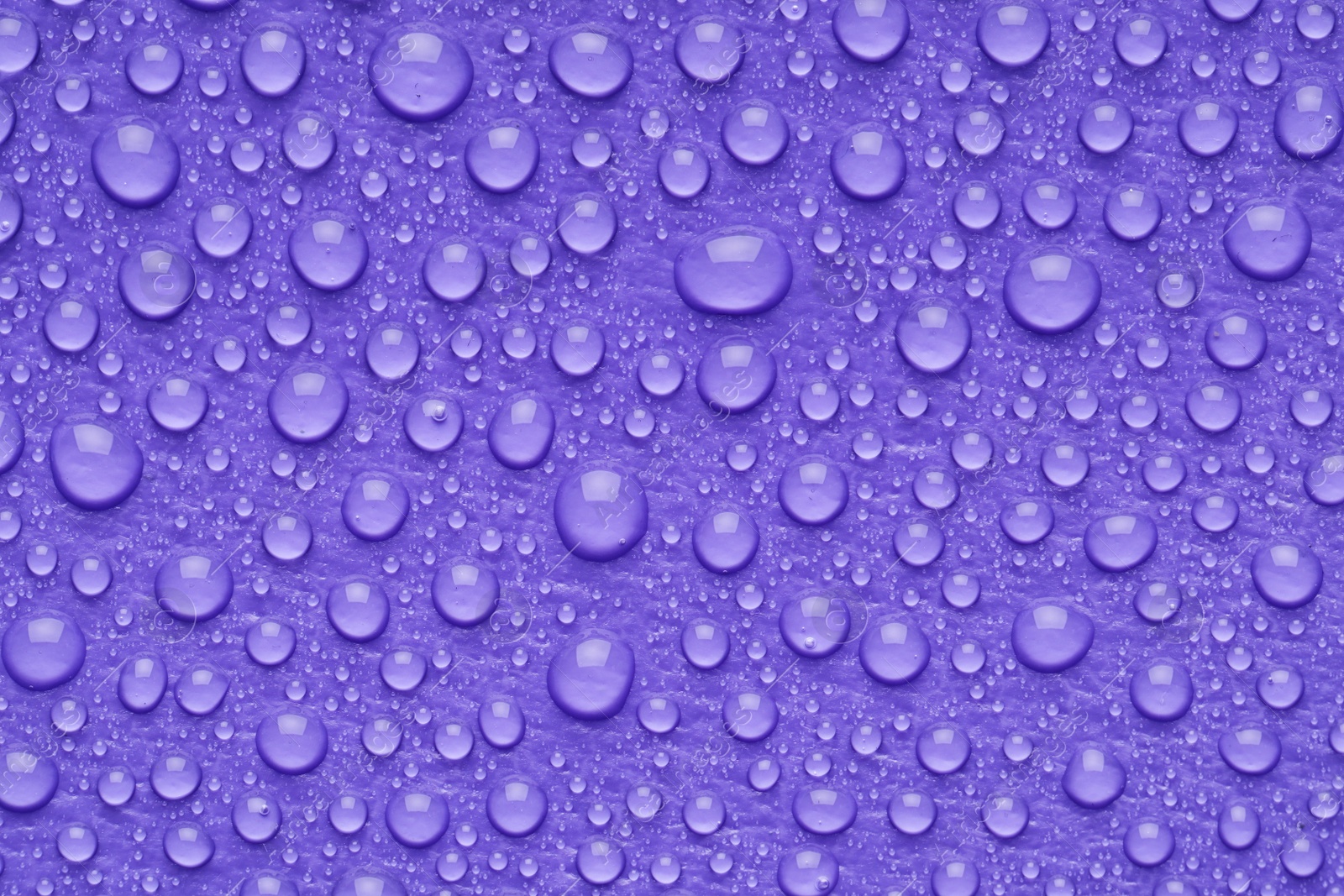 Photo of Water drops on lilac background, top view