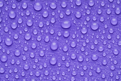 Photo of Water drops on lilac background, top view