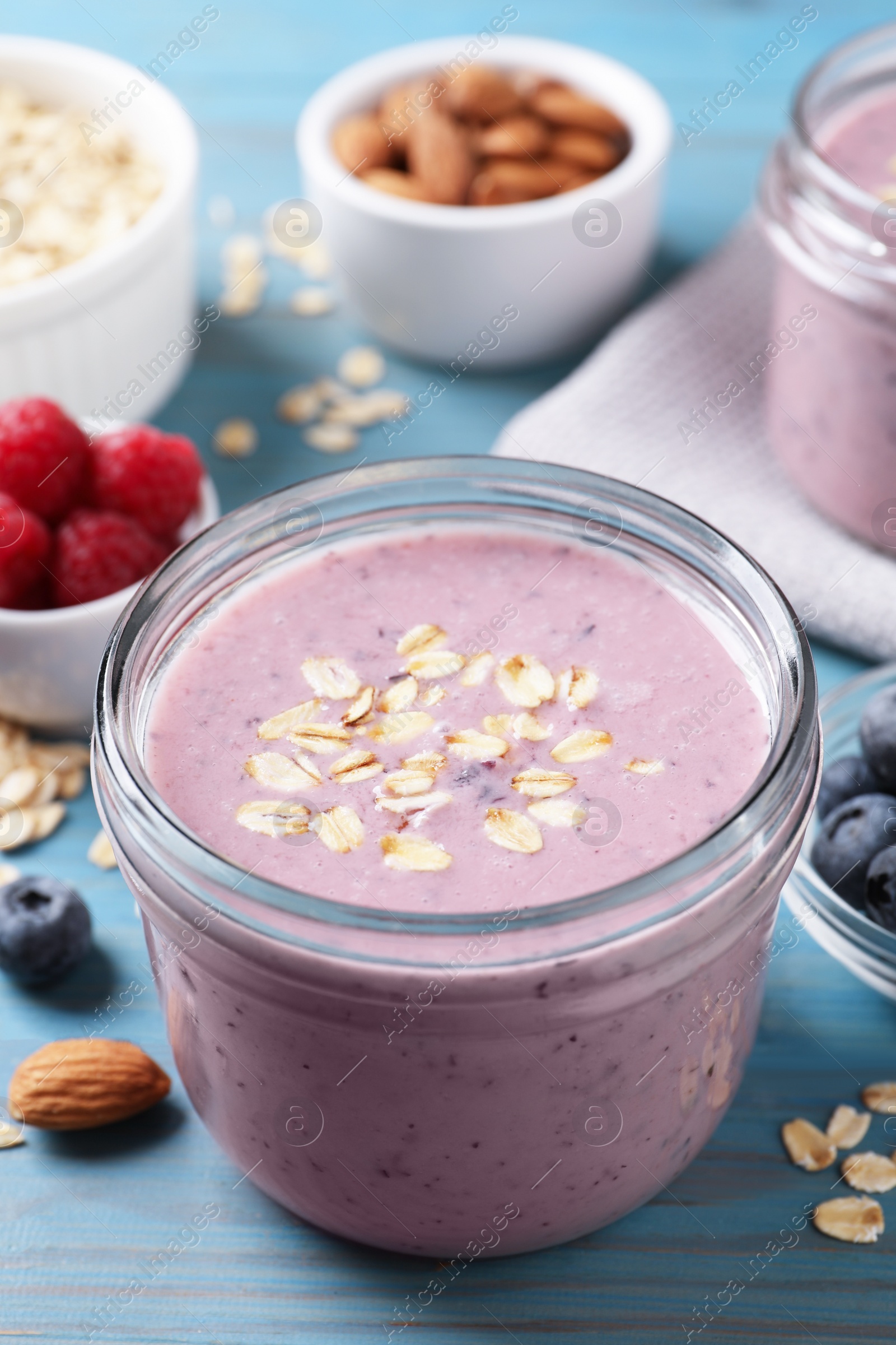 Photo of Tasty berry smoothie with oatmeal on light blue wooden table, closeup