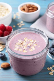 Photo of Tasty berry smoothie with oatmeal on light blue wooden table, closeup