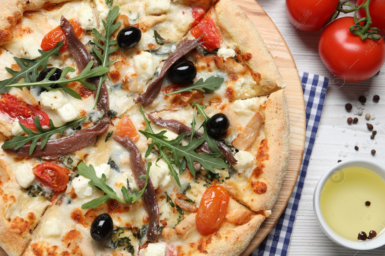 Photo of Tasty pizza with anchovies and ingredients on white wooden table, flat lay