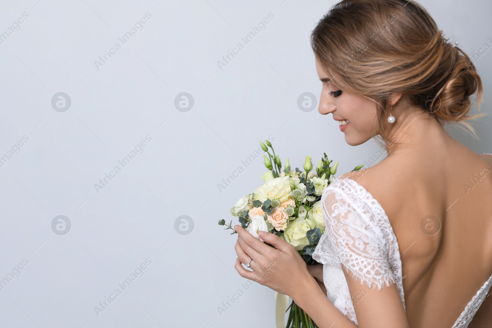 Photo of Young bride with beautiful wedding bouquet on light grey background. Space for text