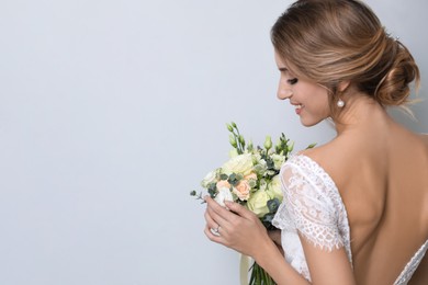 Photo of Young bride with beautiful wedding bouquet on light grey background. Space for text