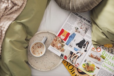 Aromatic coffee and magazines on bed with linens indoors, flat lay