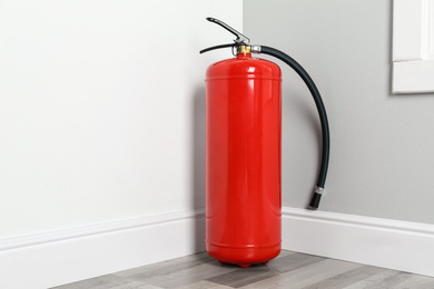 Photo of Fire extinguisher on floor in corner indoors