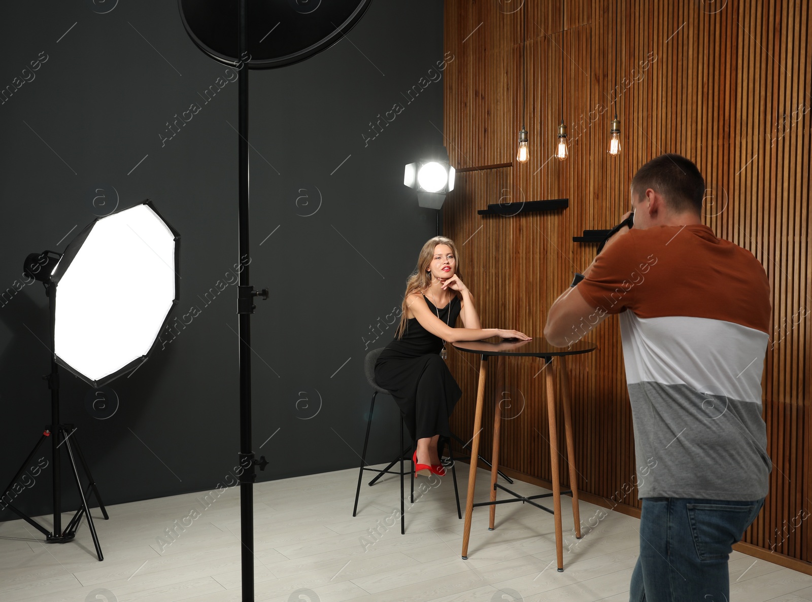 Photo of Professional photographer taking picture of young woman in modern studio