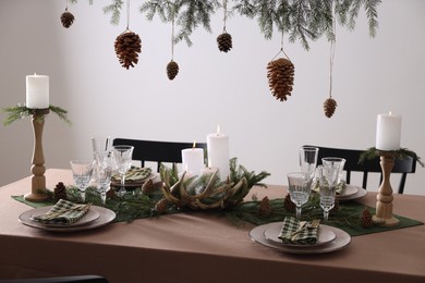 Photo of Christmas table setting with burning candles and other festive decor
