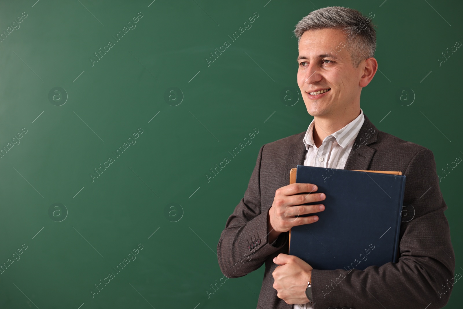 Photo of Teacher with notebooks near chalkboard, space for text