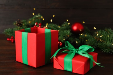 Red gift box with green bow and Christmas decor on wooden table