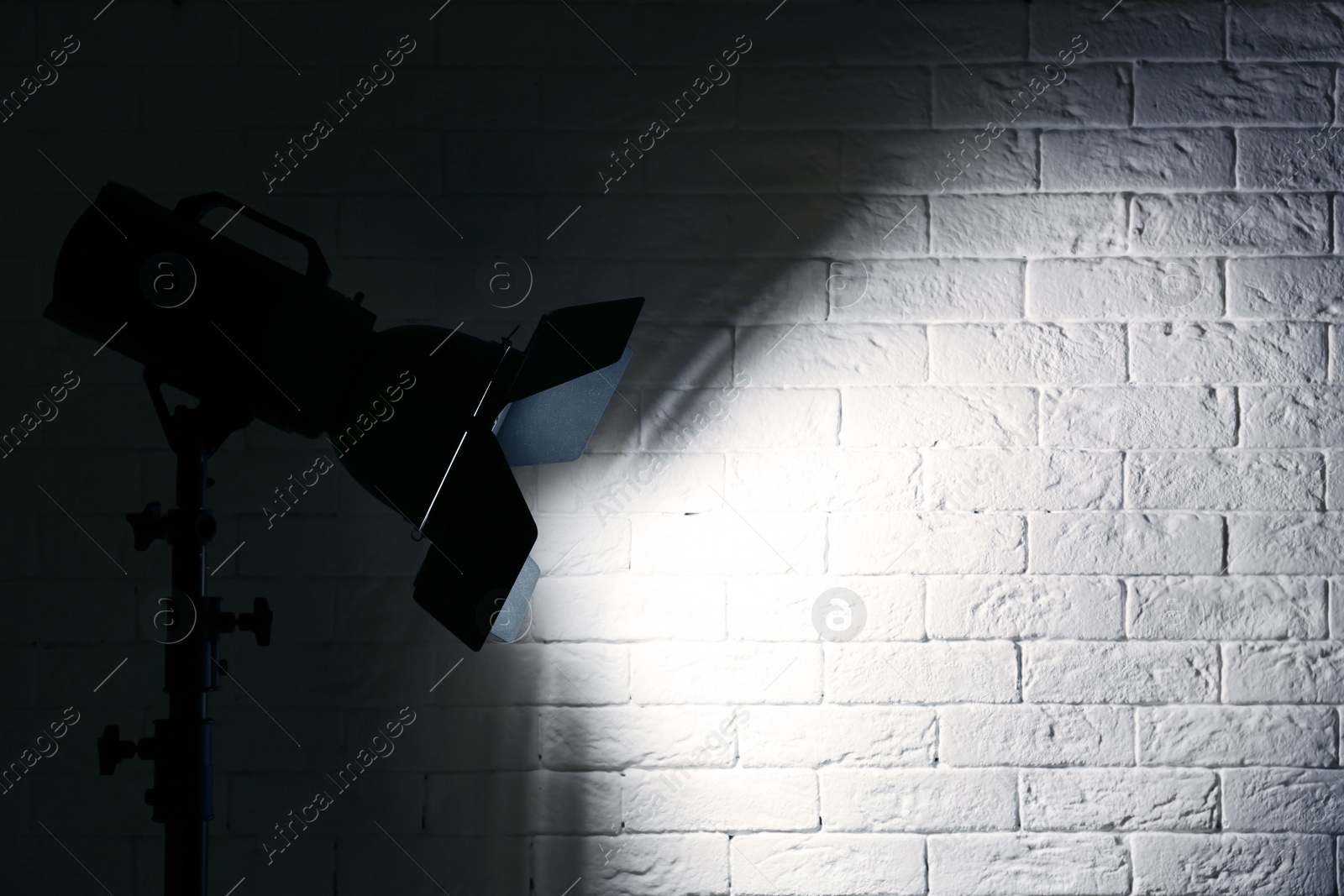 Photo of Professional photo studio lighting equipment near brick wall. Space for text