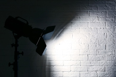 Professional photo studio lighting equipment near brick wall. Space for text