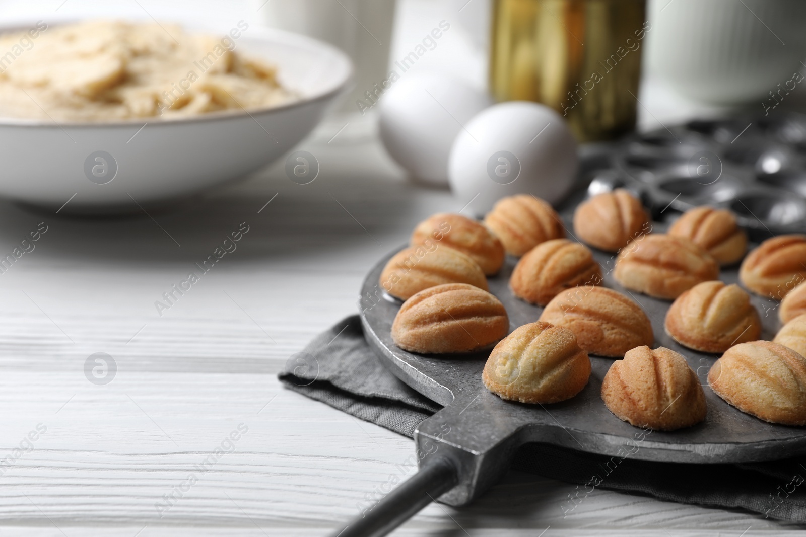 Photo of Delicious walnut shaped cookies and ingredients on white wooden table, closeup. Space for text