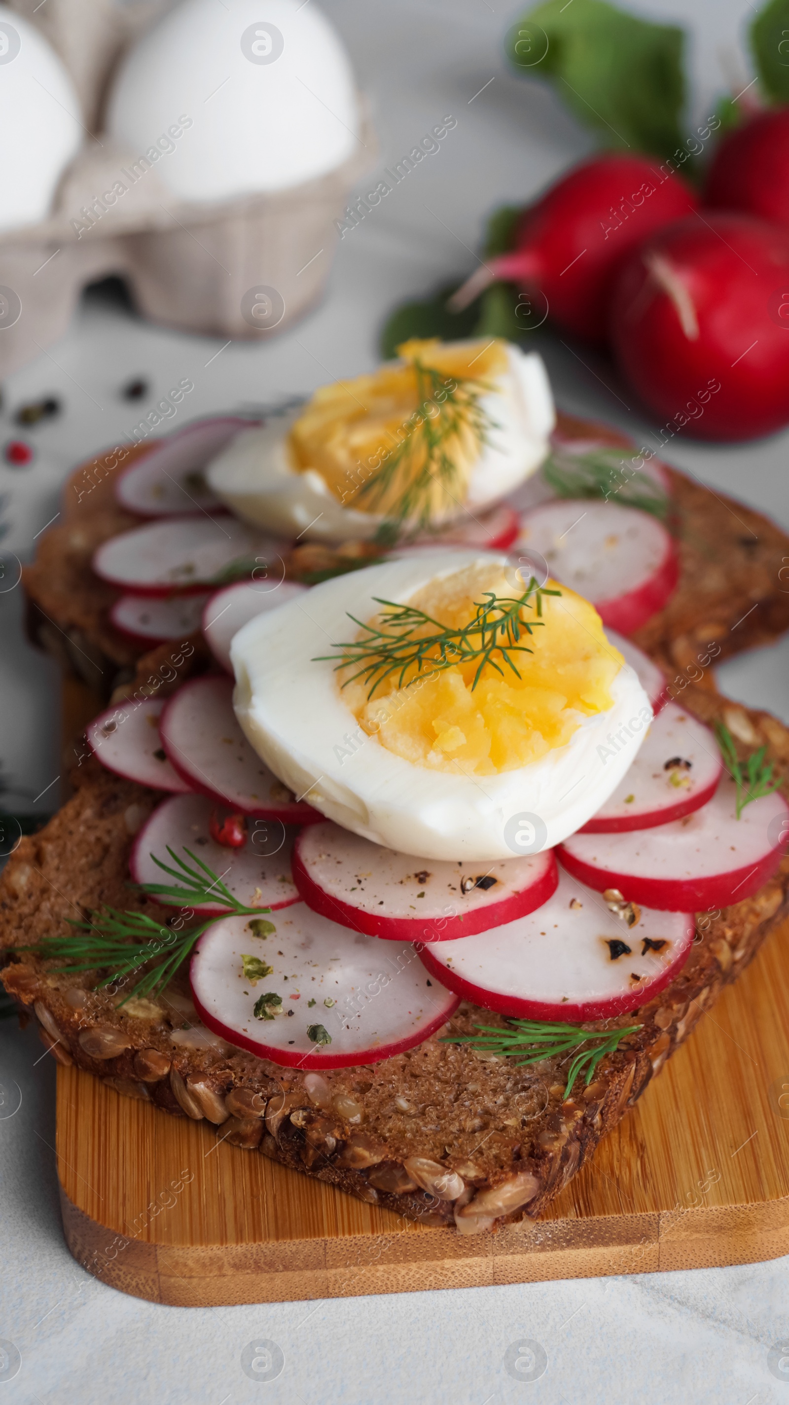 Photo of Tasty sandwiches with boiled egg and radish on white table, closeup