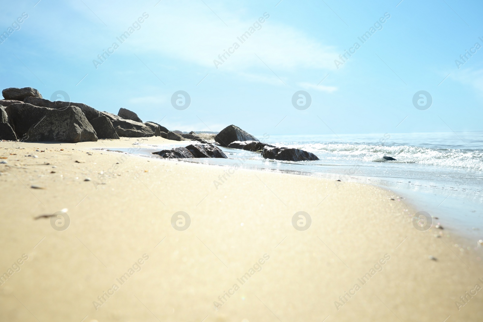 Photo of Sandy beach with rocks near sea on sunny day, closeup