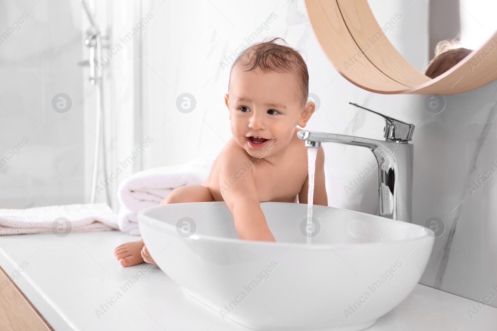 Photo of Cute little baby playing in bathroom at home