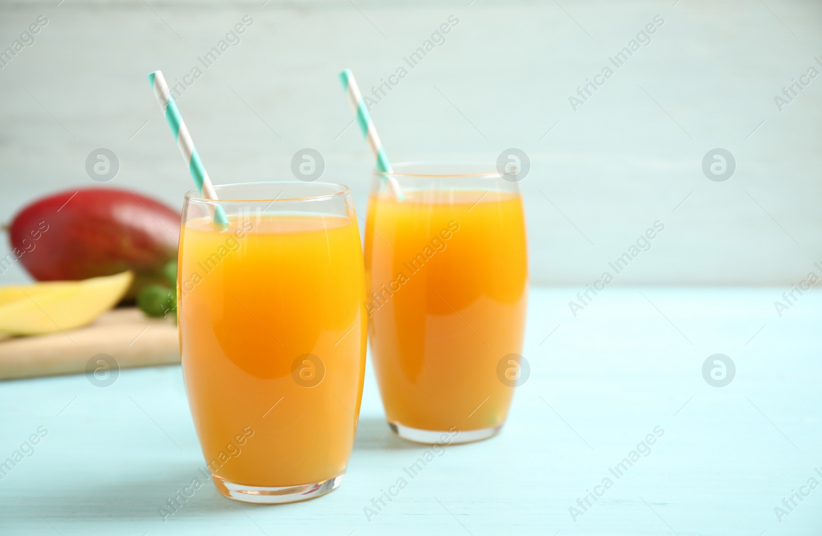 Photo of Fresh delicious mango drink on light blue wooden table