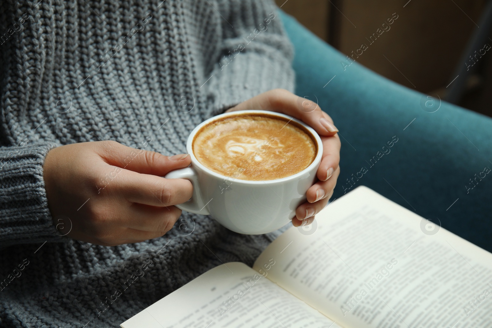 Photo of Woman with cup of coffee reading book at home, closeup