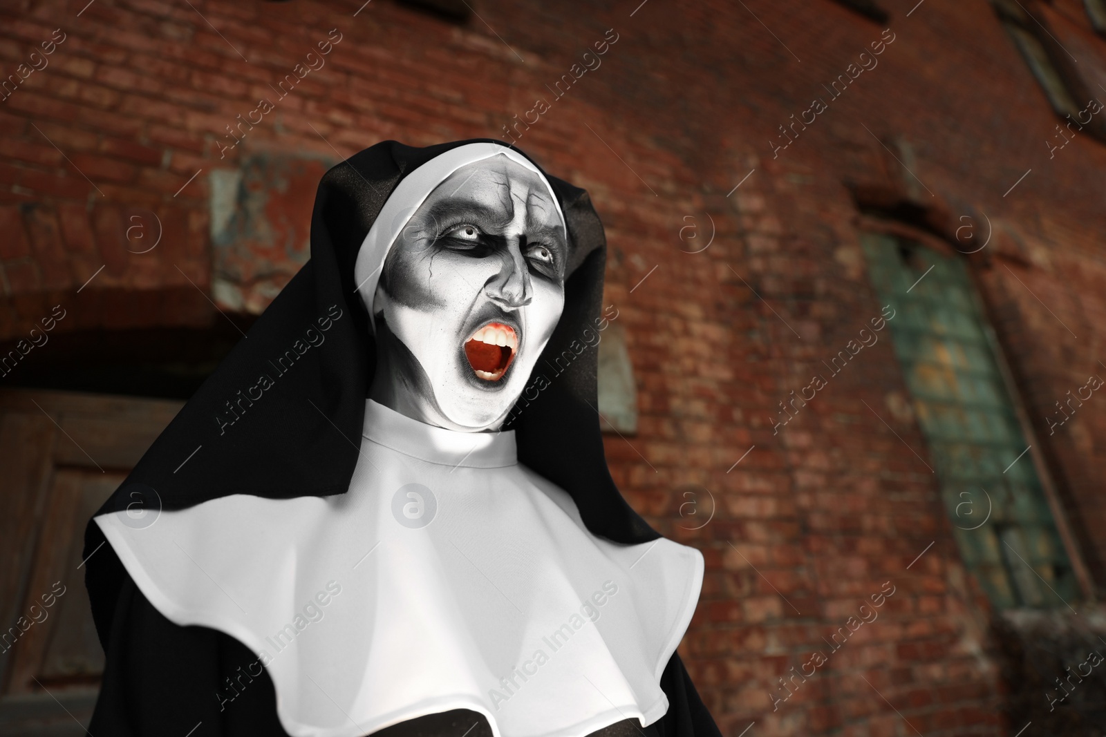 Photo of Portrait of scary devilish nun outdoors, space for text. Halloween party look