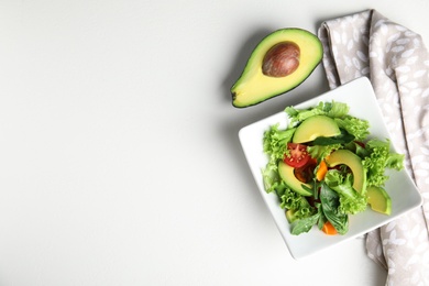 Delicious avocado salad in bowl on white table, flat lay. Space for text