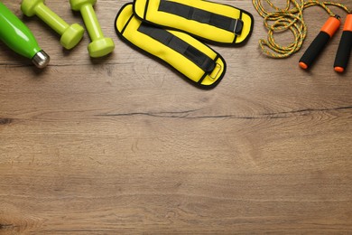 Yellow weighting agents and sport equipment on wooden table, flat lay. Space for text