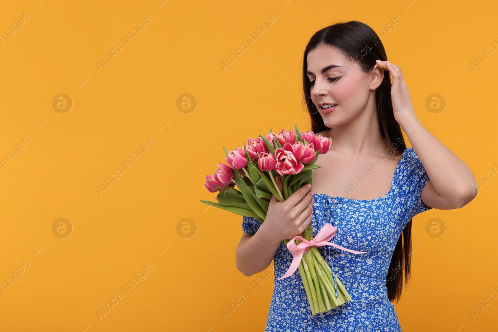 Photo of Happy young woman with beautiful bouquet on orange background. Space for text