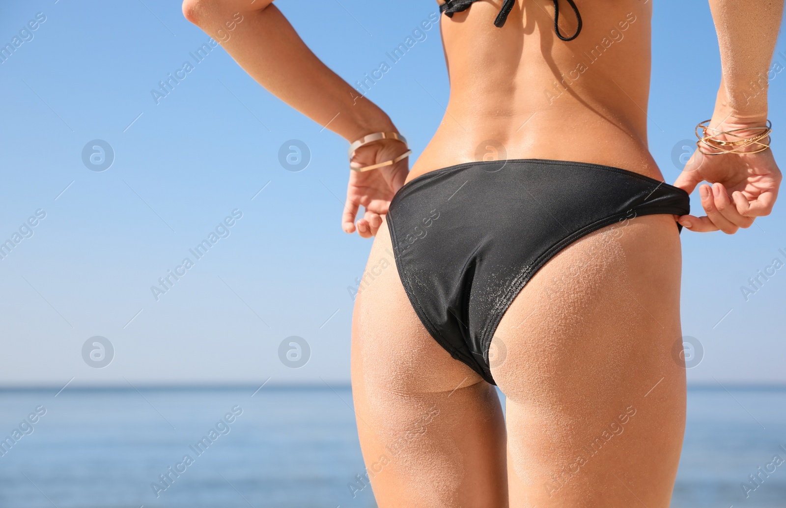 Photo of Young woman with beautiful body on beach, closeup. Space for text