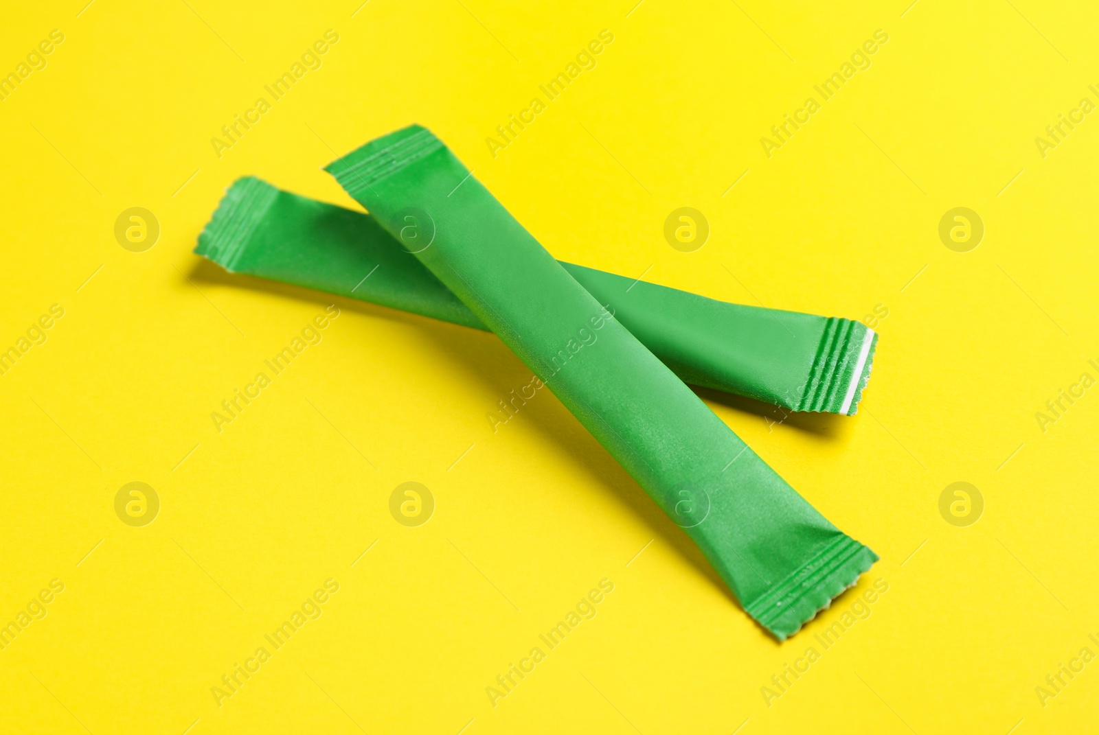 Photo of Green sticks of sugar on yellow background