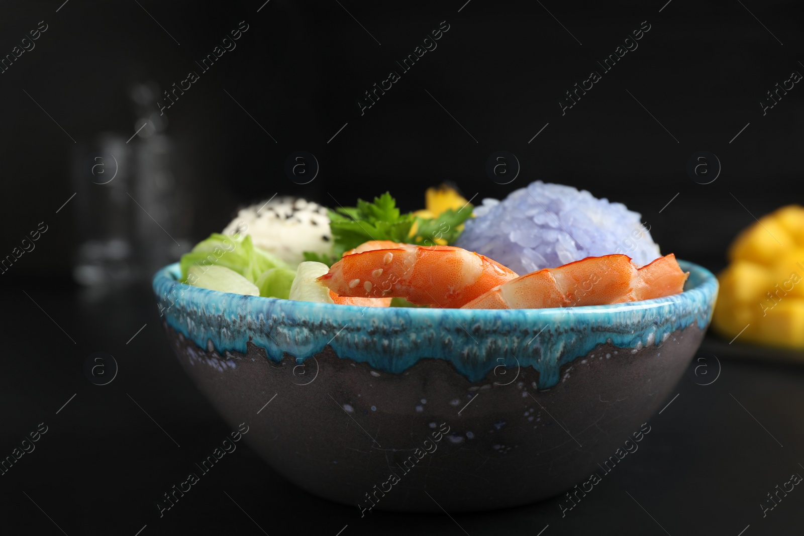 Photo of Delicious poke bowl served on black table, closeup