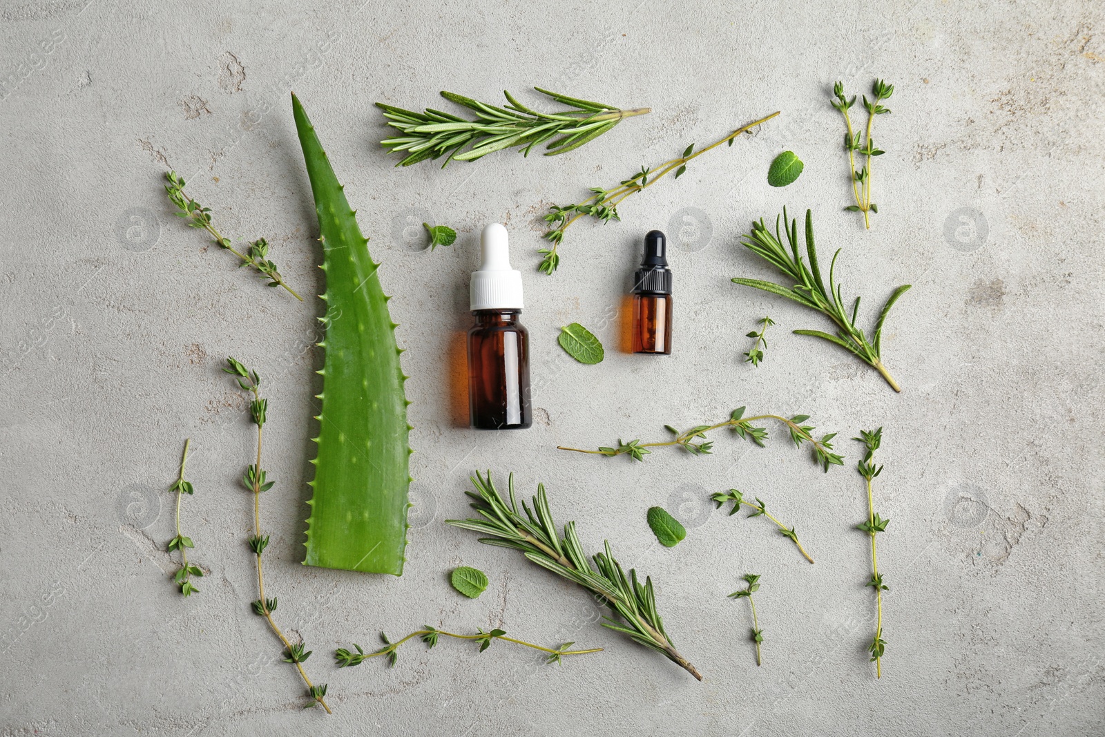 Photo of Bottles with essential oils and fresh herbs on light background, flat lay