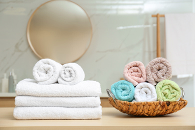 Photo of Fresh soft towels on wooden table in bathroom