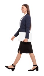 Young businesswoman with laptop walking on white background