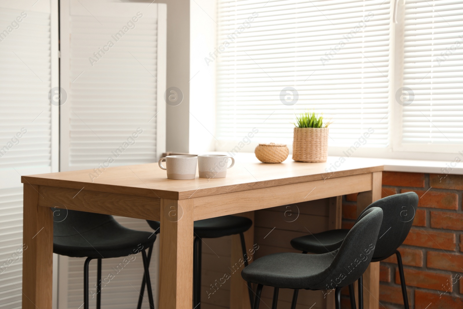 Photo of Stylish dining room interior with modern table set and window blinds