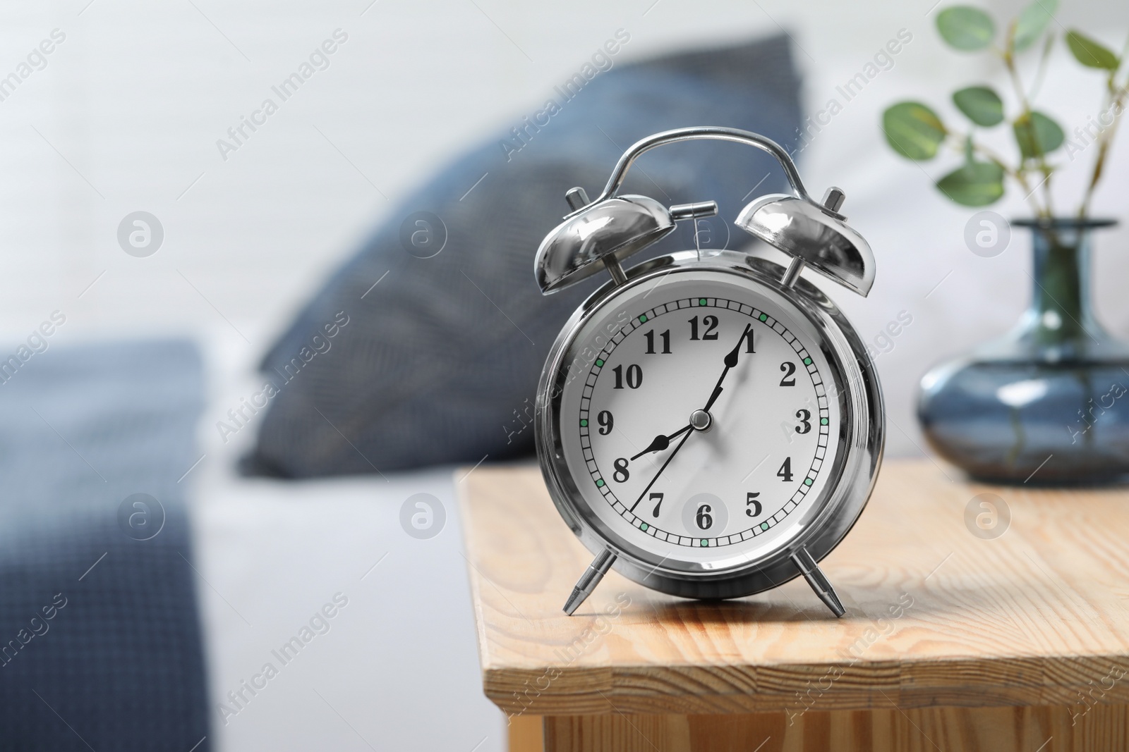 Photo of Silver alarm clock on wooden nightstand in bedroom, space for text