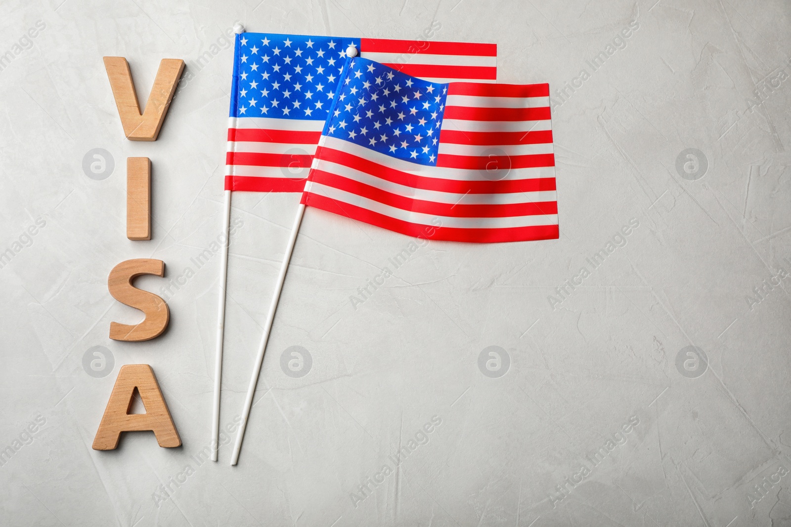 Photo of Flat lay composition with word VISA and flags of USA on gray background. Space for text