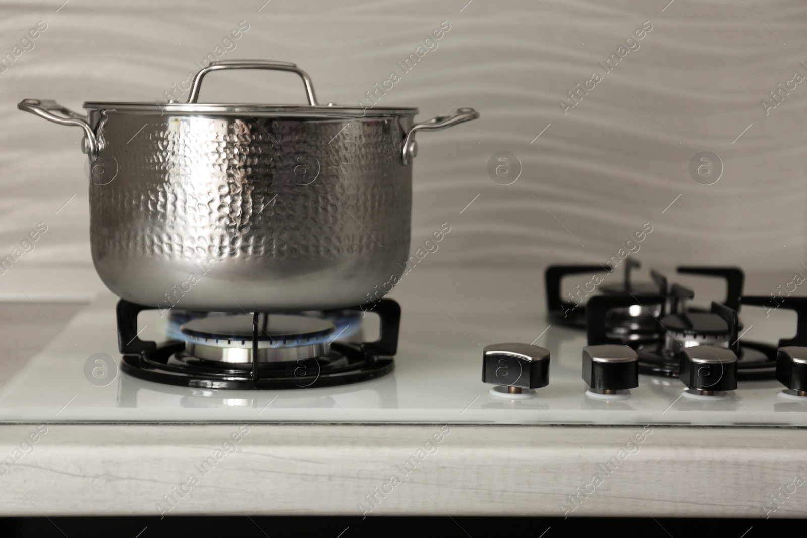 Photo of Shiny steel saucepan on modern gas stove. Space for text