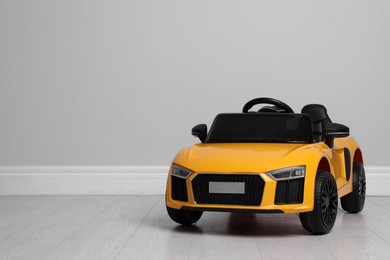 Photo of Child's electric toy car near light wall indoors. Space for text