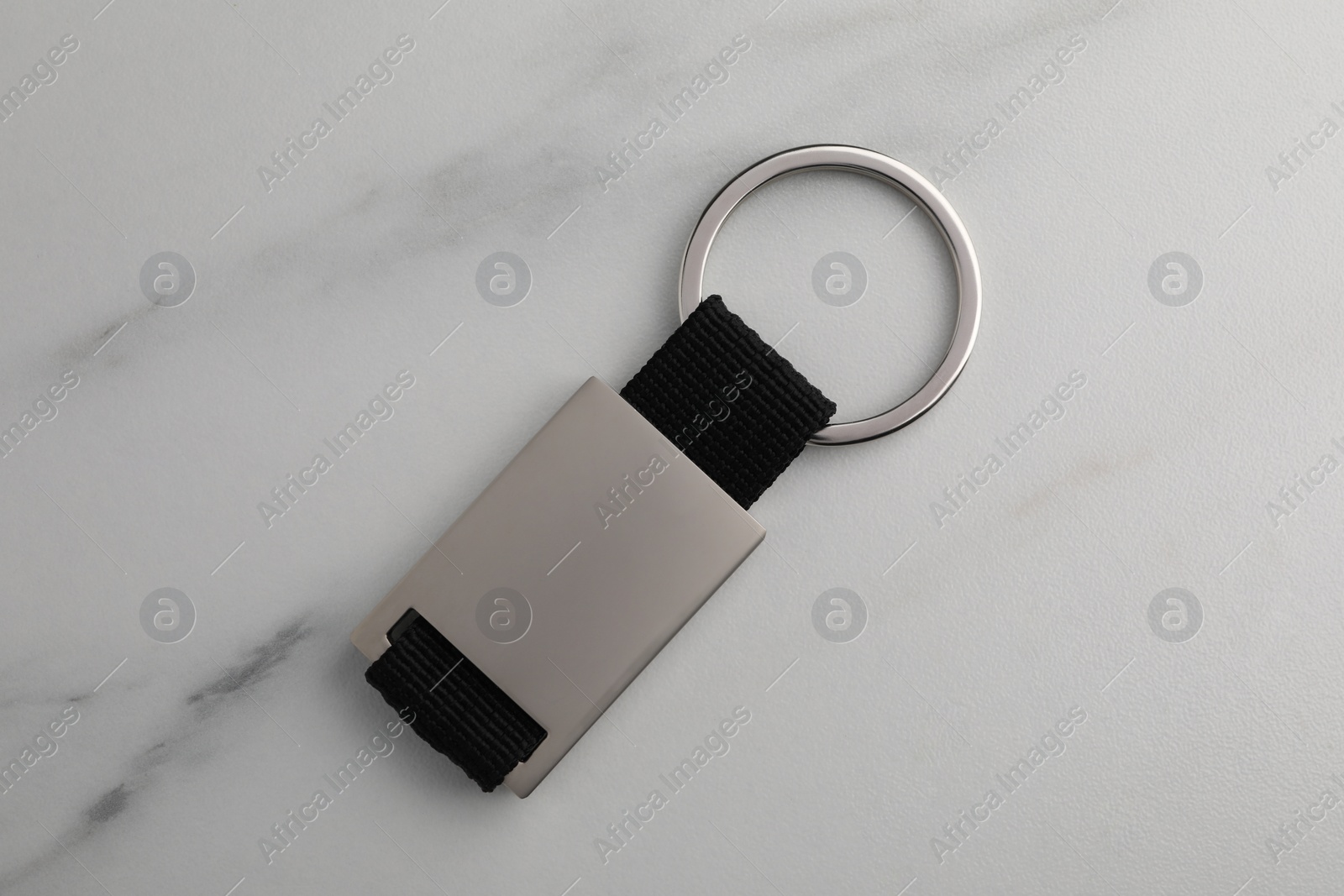 Photo of Metal keychain on white marble table, top view