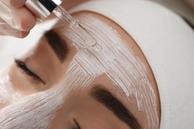 Photo of Young woman during face peeling procedure in salon, closeup