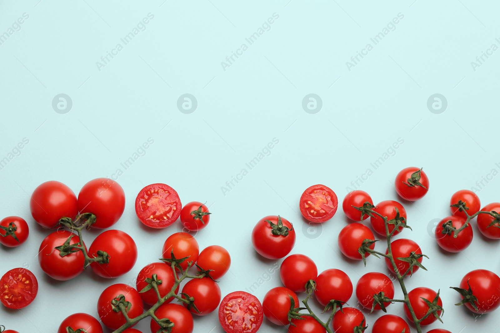 Photo of Fresh cherry tomatoes on light blue background, flat lay. Space for text