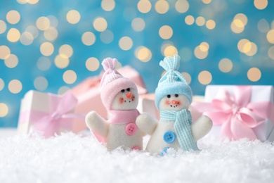 Photo of Snowman toys on snow against blurred festive lights. Christmas decoration