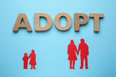 Figures of parents with children and word Adopt on light blue background, flat lay