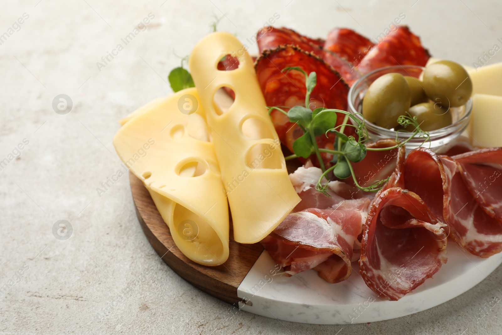Photo of Serving board with delicious cured ham, cheese, sausage and olives on light table, closeup