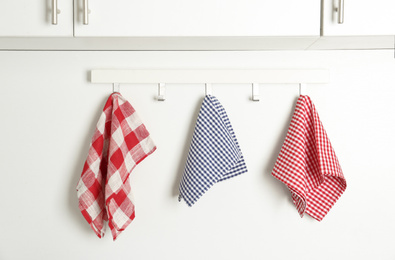 Photo of Different kitchen towels hanging on hook rack indoors