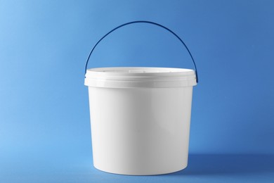 Photo of One plastic bucket with lid on light blue background