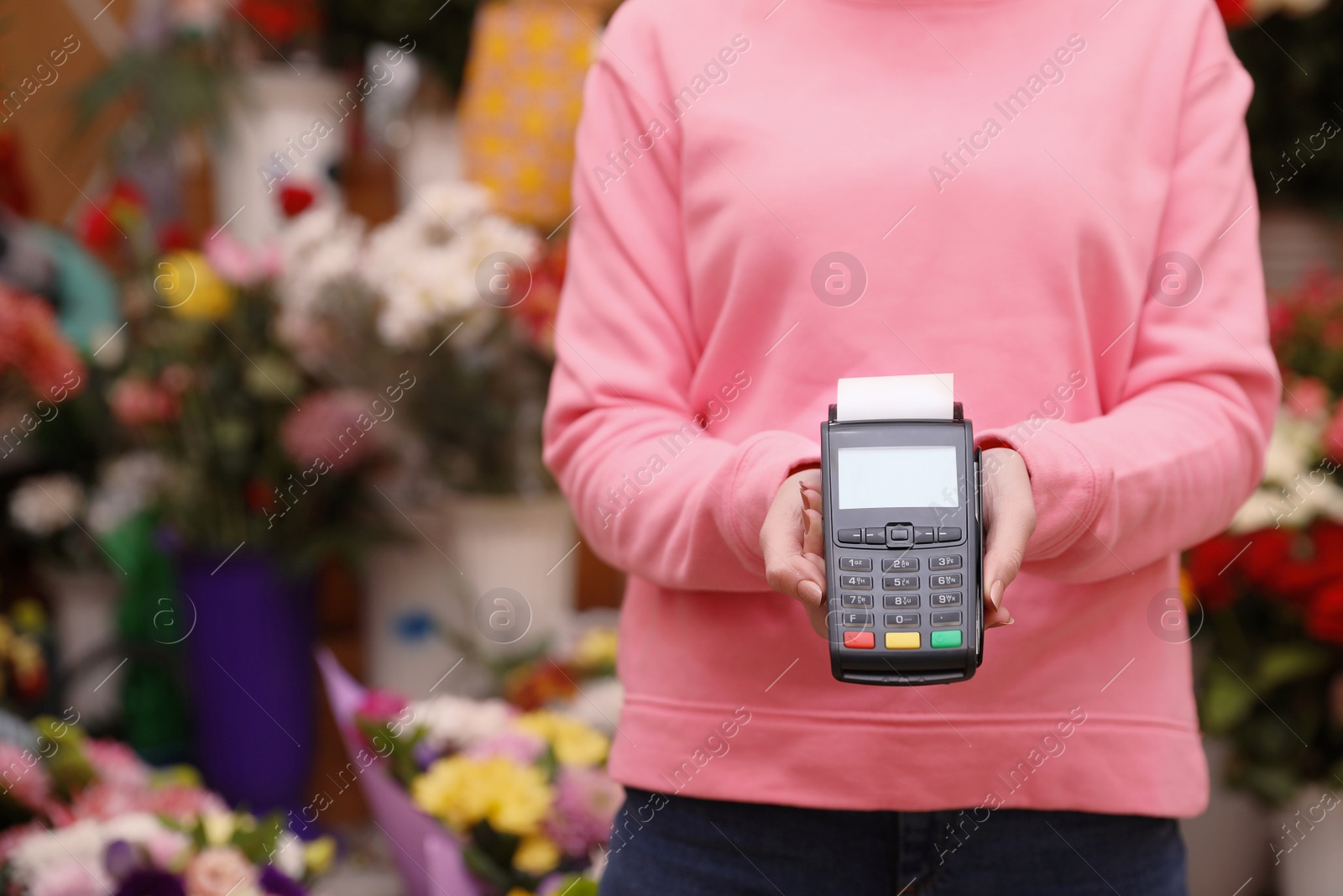 Photo of Woman holding payment terminal in floral shop, closeup. Space for text