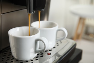 Photo of Espresso machine pouring coffee into cups against blurred background, closeup. Space for text