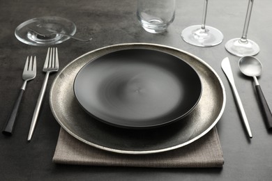 Stylish setting with cutlery, glasses and plates on black table